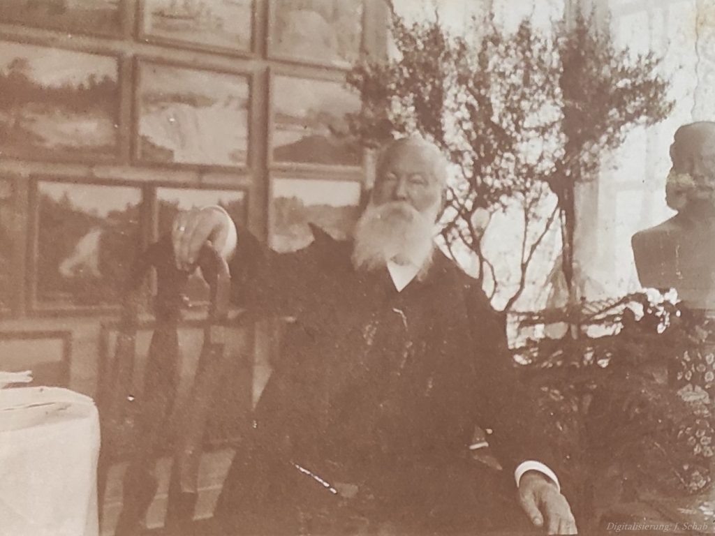 Foto des Künstlers Ernst Seyffardt in hohem Alter - mit Gemälden im Hintergrund